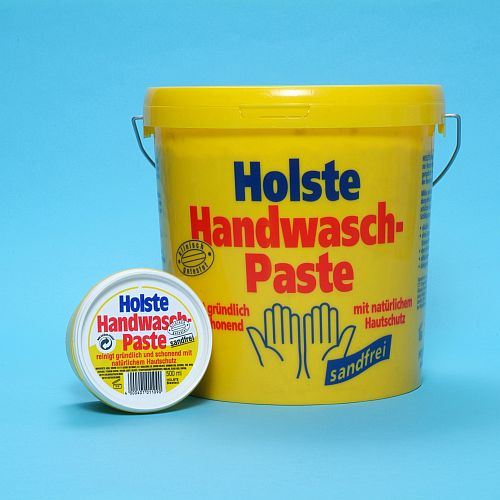 Żółte opakowanie pasty do mycia rąk Holste Handwasch-Paste w wiaderku i mniejszym pojemniku, na jednolitym, błękitnym tle.